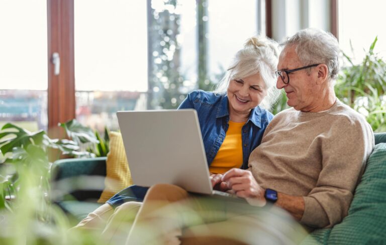 Paar betrachtet einen Laptop, auf dem Sofa sitzend